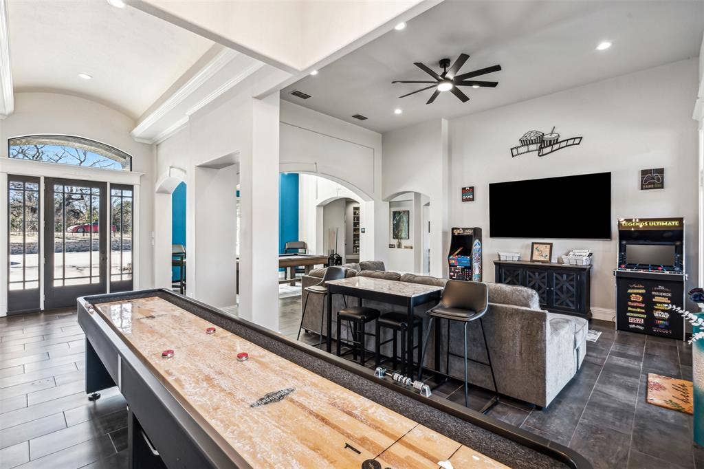 2100 Gene Court, Granbury, TX 76048 Spacious entertainment room featuring dark wood-finish flooring, high ceilings with recessed lighting, and a modern ceiling fan