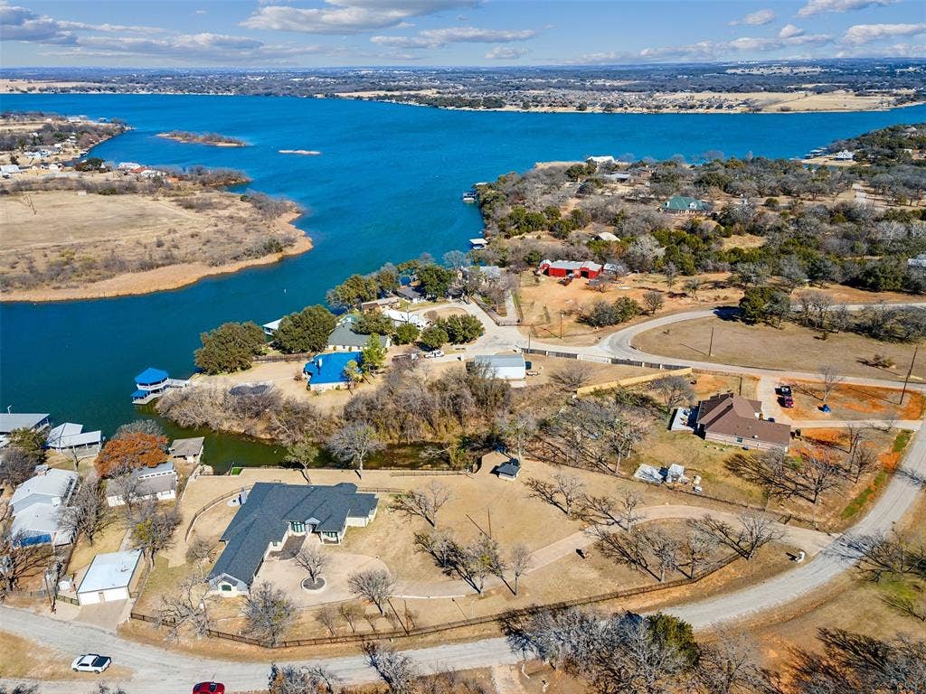 2100 Gene Court, Granbury, TX 76048 Aerial overview of a waterfront community featuring a large body of water, multiple residential properties, and a natural landscape