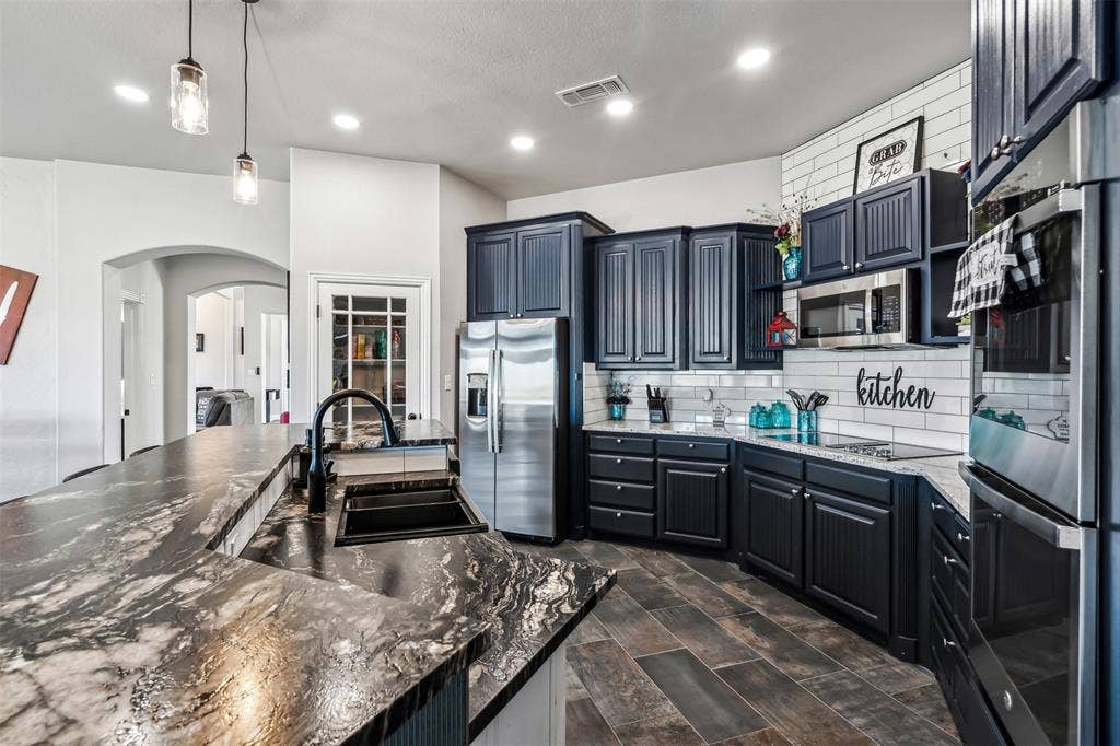 2100 Gene Court, Granbury, TX 76048 Kitchen featuring dark wood-finish cabinetry, stainless steel appliances, and wood-finish tile flooring