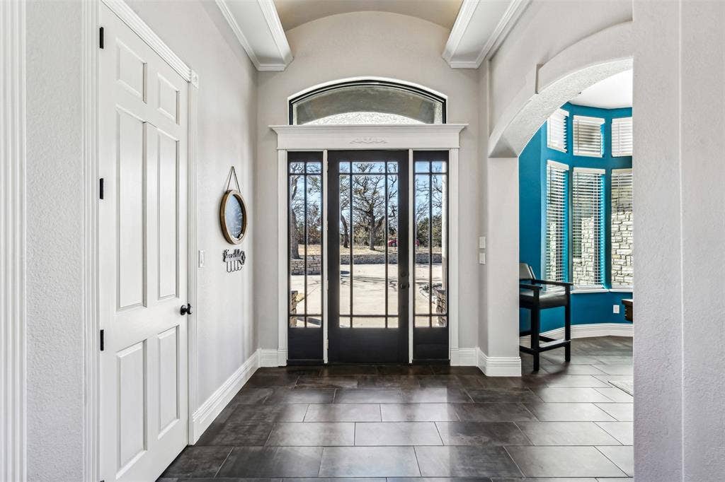 2100 Gene Court, Granbury, TX 76048 Grand entry featuring dark-framed French doors with an arched transom, leading to an exterior stone facade