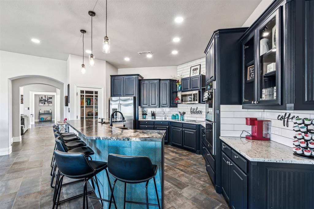 2100 Gene Court, Granbury, TX 76048 Contemporary kitchen featuring dark wood cabinetry and a large island with a substantial countertop