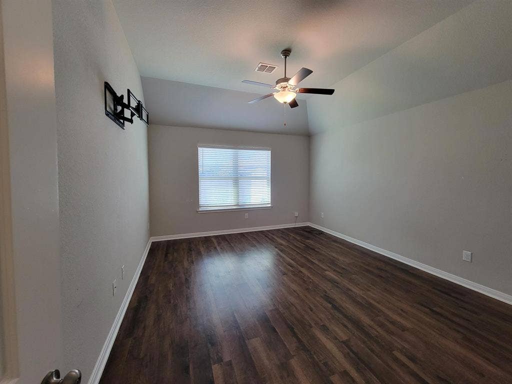 1106 Placid Circle, Waco, TX 76706 Spacious room featuring vaulted ceilings, a ceiling fan with integrated lighting, wood-finish flooring, and a window with horizontal blinds