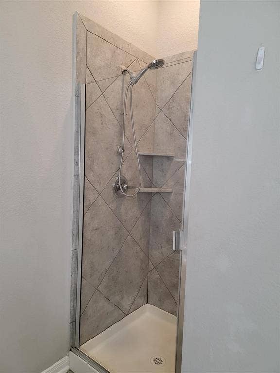 1106 Placid Circle, Waco, TX 76706 Shower enclosure featuring a frameless glass door, diagonal tile surround, dual showerheads, and built-in shelving
