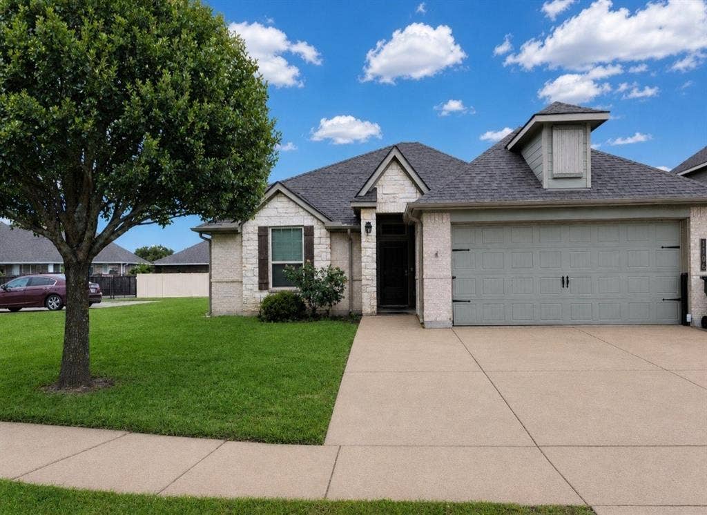 1106 Placid Circle, Waco, TX 76706 Single-story residence featuring a stone and stucco exterior, an attached two-car garage with decorative hardware, an asphalt shingle roof, and a concrete driveway