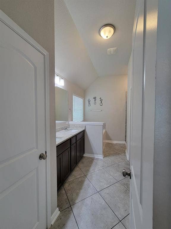 1106 Placid Circle, Waco, TX 76706 Spacious bathroom with dual vanities, stone-finish countertops, dark wood cabinetry, and neutral-toned tile flooring