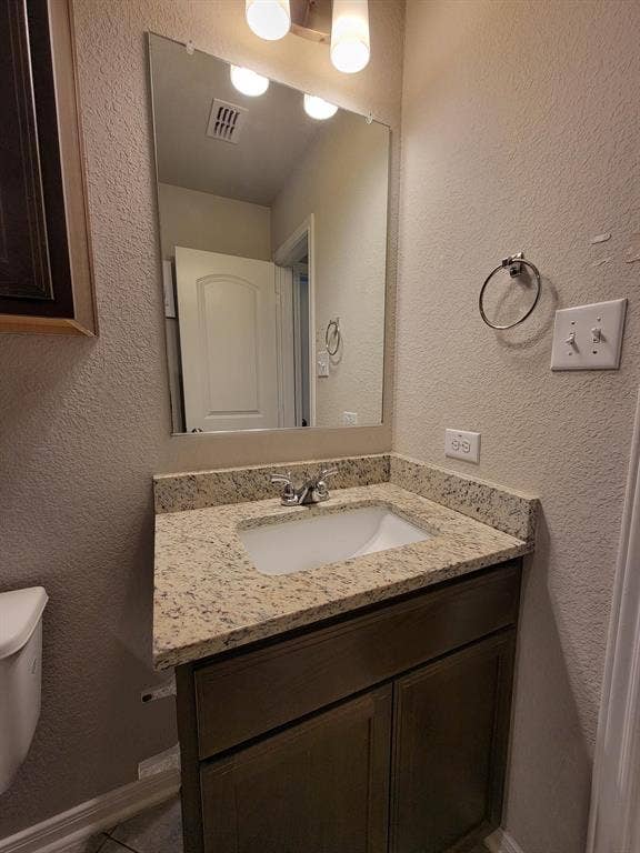 1106 Placid Circle, Waco, TX 76706 Bathroom vanity featuring a speckled countertop, undermount sink, and dark wood-finish cabinetry