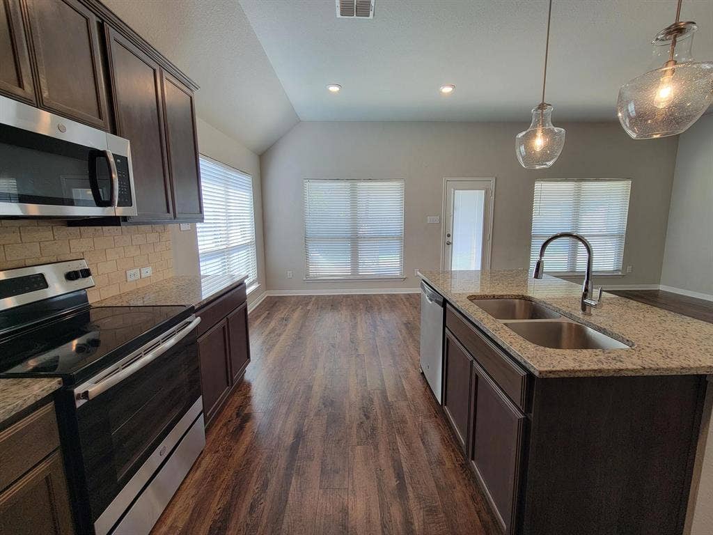 1106 Placid Circle, Waco, TX 76706 Kitchen featuring dark wood cabinetry, stainless steel appliances, speckled stone countertops, and a subway tile backsplash