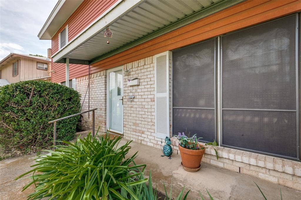3013 Margo Drive, Mesquite, TX 75150 White brick exterior with a covered entryway, featuring an opaque glass entry door and a metal handrail