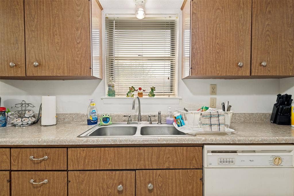 3013 Margo Drive, Mesquite, TX 75150 Kitchen featuring wood-finish cabinetry, a double-basin stainless steel sink, and laminate countertops