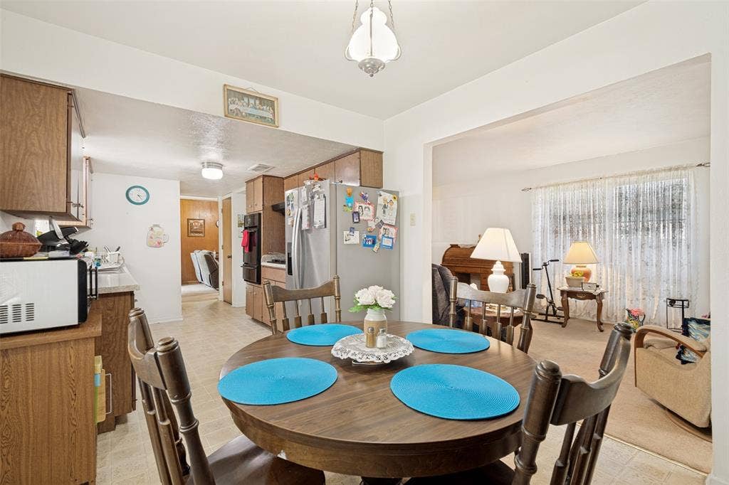 3013 Margo Drive, Mesquite, TX 75150 Dining area featuring a central wooden table, wood-finish flooring, and an overhead pendant light fixture