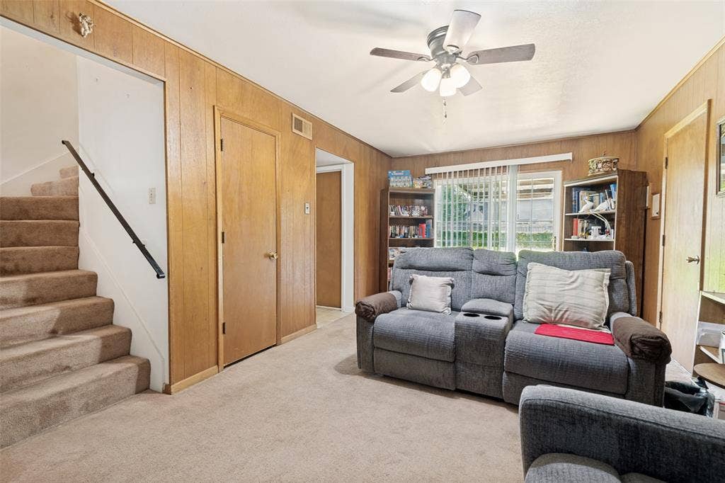 3013 Margo Drive, Mesquite, TX 75150 Living area featuring wood-finish wall paneling, carpeted flooring, and a ceiling fan