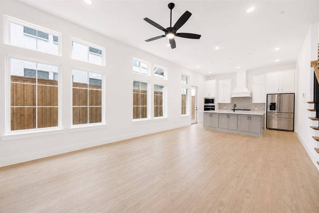 11965 Brubaker Drive, Frisco, TX 75033 Open-concept living area featuring wood-finish flooring, a contemporary ceiling fan, recessed lighting, and an expansive window array