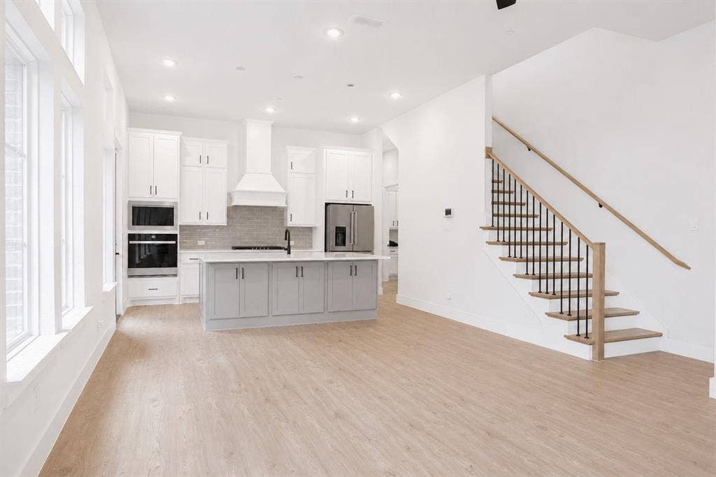 11965 Brubaker Drive, Frisco, TX 75033 Open-concept kitchen with white cabinetry, a light gray island, stainless steel appliances, and wood-finish flooring