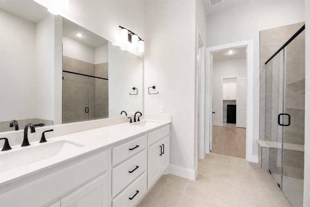 11965 Brubaker Drive, Frisco, TX 75033 Double vanity featuring white cabinetry, integrated sinks, and matte black fixtures