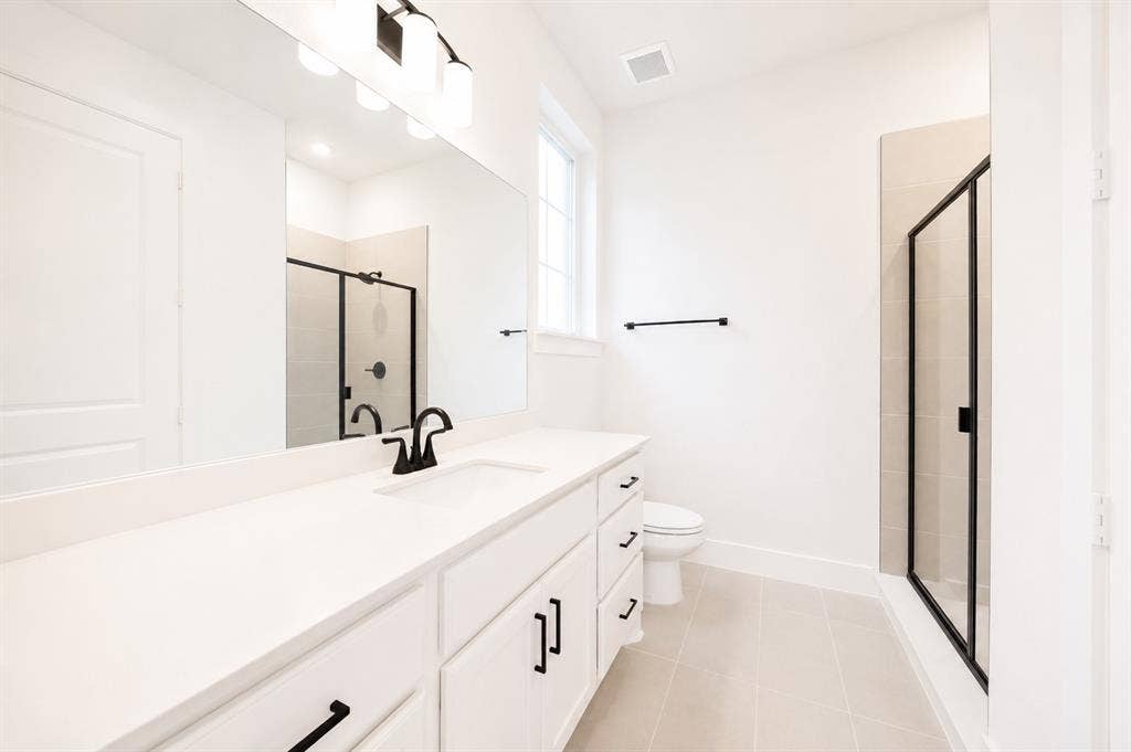 11965 Brubaker Drive, Frisco, TX 75033 Contemporary bathroom featuring a spacious vanity with an undermount sink, white cabinetry, and matte black hardware