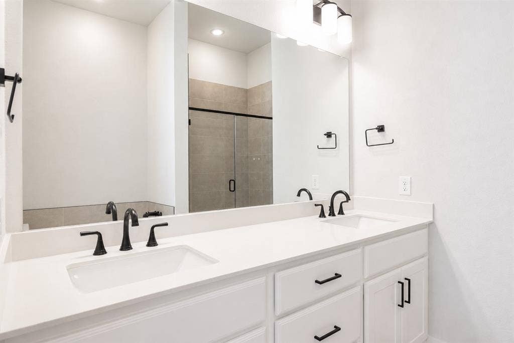 11965 Brubaker Drive, Frisco, TX 75033 Dual vanity featuring white countertops, undermount sinks, and matte black fixtures