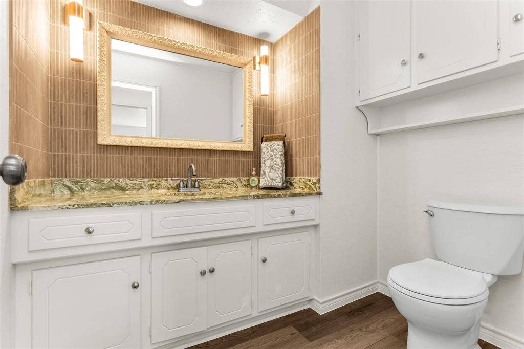 101 Hollyhill Lane, Denton, TX 76205 Vanity with a green-veined countertop, white cabinetry, and a decorative framed mirror