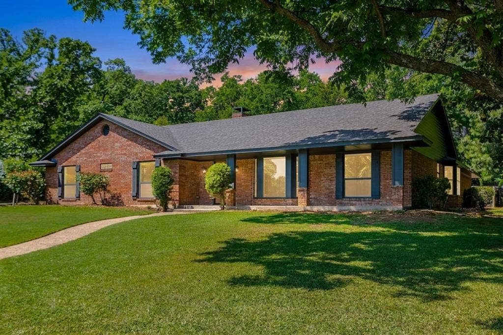 101 Hollyhill Lane, Denton, TX 76205 Brick exterior featuring a dark gray shingle roof and a covered entry