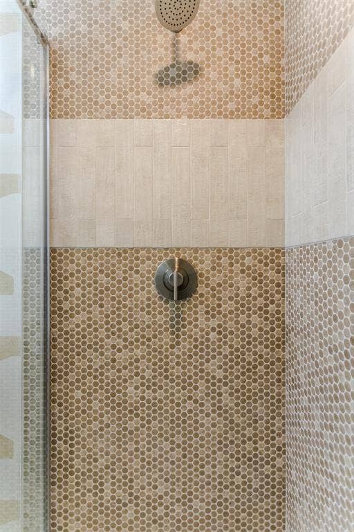 101 Hollyhill Lane, Denton, TX 76205 Shower stall featuring hexagonal mosaic tile, a contrasting horizontal band of textured rectangular tile, and a brushed metal shower head and control