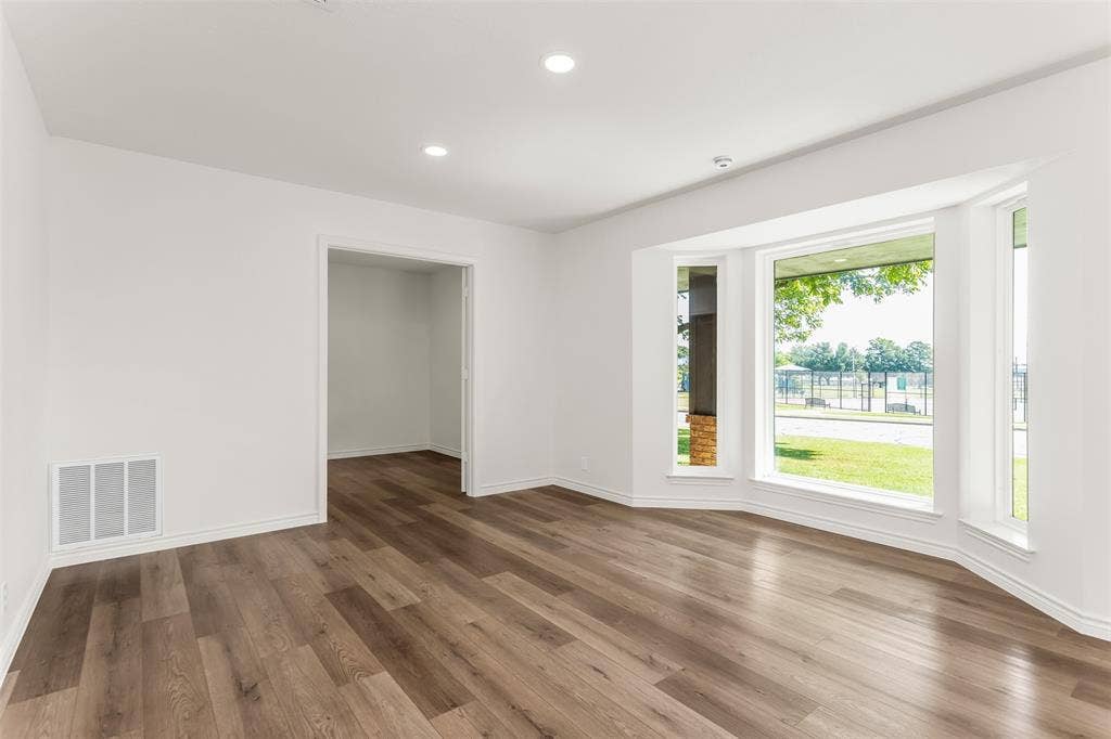 101 Hollyhill Lane, Denton, TX 76205 Spacious room featuring a bay window, wood-finish flooring, recessed lighting, and white baseboards