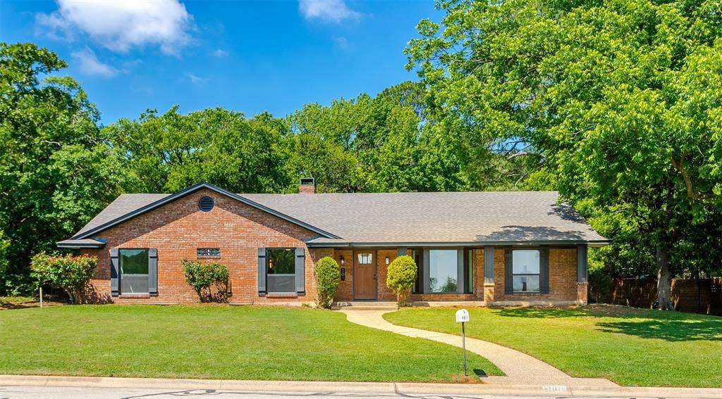 101 Hollyhill Lane, Denton, TX 76205 Brick exterior with a gray shingle roof and dark shutters