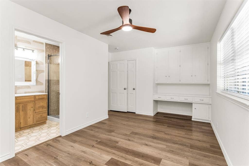 101 Hollyhill Lane, Denton, TX 76205 Bedroom featuring wood-finish flooring, a built-in desk with overhead cabinetry, and a window with blinds
