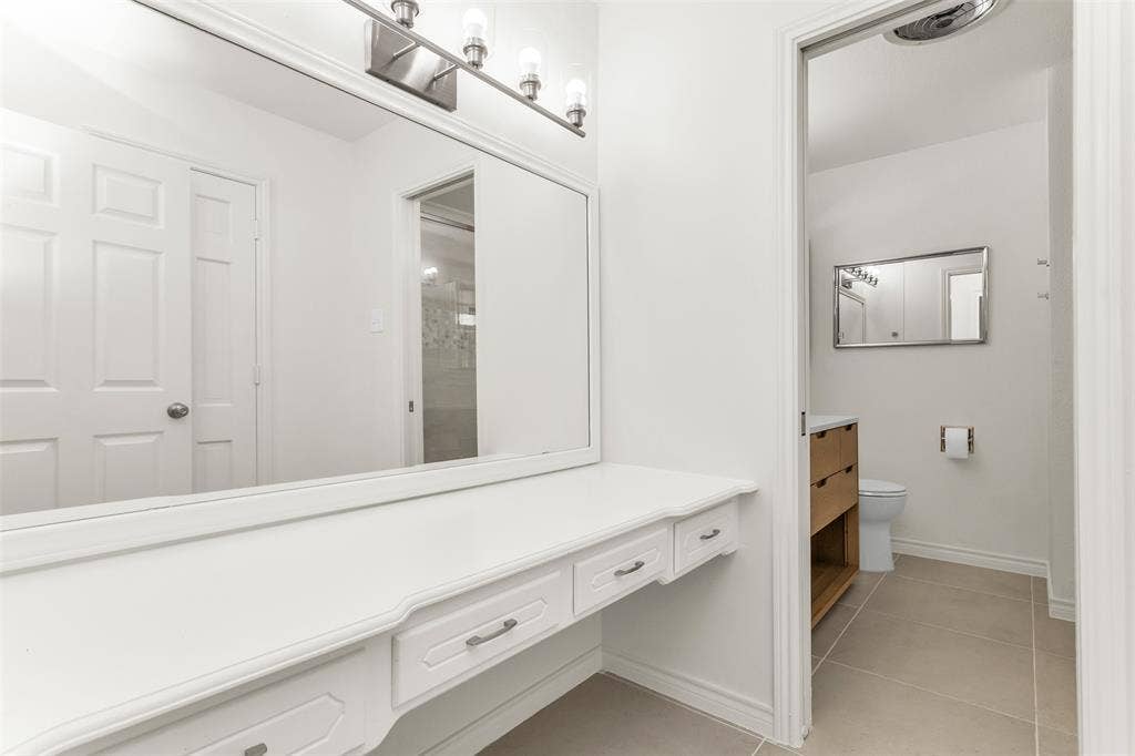 101 Hollyhill Lane, Denton, TX 76205 Integrated dressing vanity with multiple drawers, expansive mirror, and overhead lighting fixture