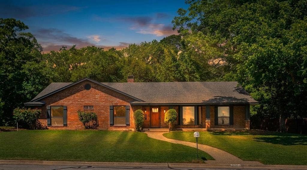 101 Hollyhill Lane, Denton, TX 76205 Brick exterior residence with a dark shingle roof and mature trees providing natural screening
