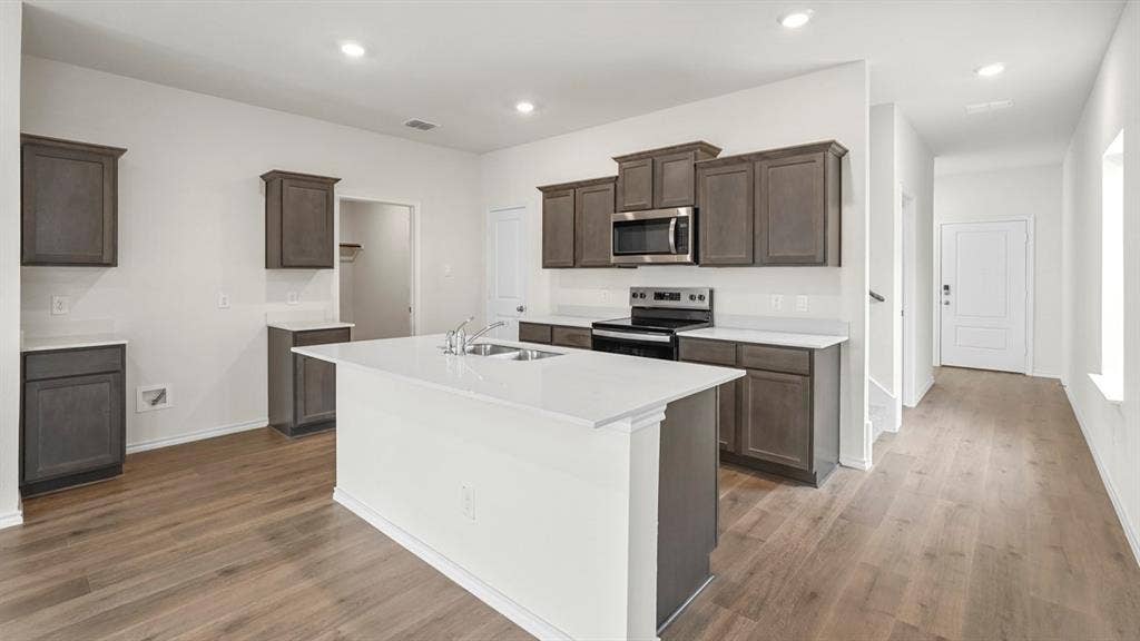 1619 Blaire Drive, Tyler, TX 75702 Contemporary kitchen featuring an expansive center island, integrated stainless steel appliances, wood-finish flooring, white countertops, and recessed lighting