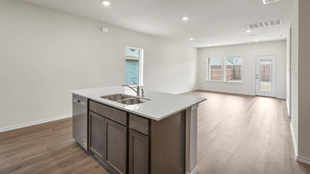 1619 Blaire Drive, Tyler, TX 75702 Kitchen island featuring a double-basin sink, stainless steel faucet, and integrated dishwasher