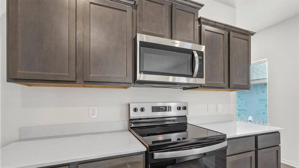 1619 Blaire Drive, Tyler, TX 75702 Kitchen featuring a stainless steel microwave, black electric range, gray shaker-style cabinetry, and light-colored countertops