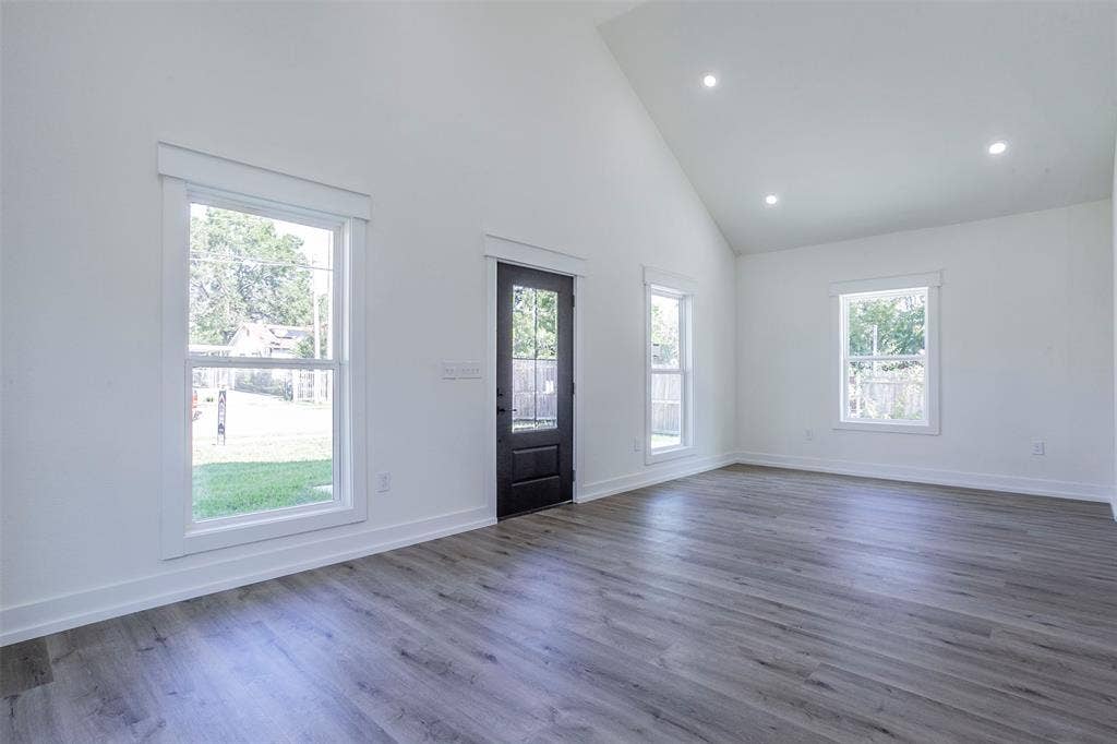 2608 Cleveland Avenue, Waco, TX 76711 Spacious room featuring vaulted ceilings, recessed lighting, wood-finish flooring, white trim, and a dark paneled door with glass inserts