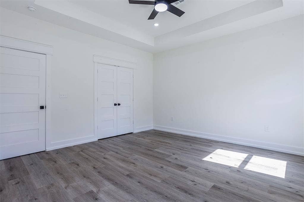 2608 Cleveland Avenue, Waco, TX 76711 Spacious room featuring wood-finish flooring, white walls, and a tray ceiling with a built-in ceiling fan