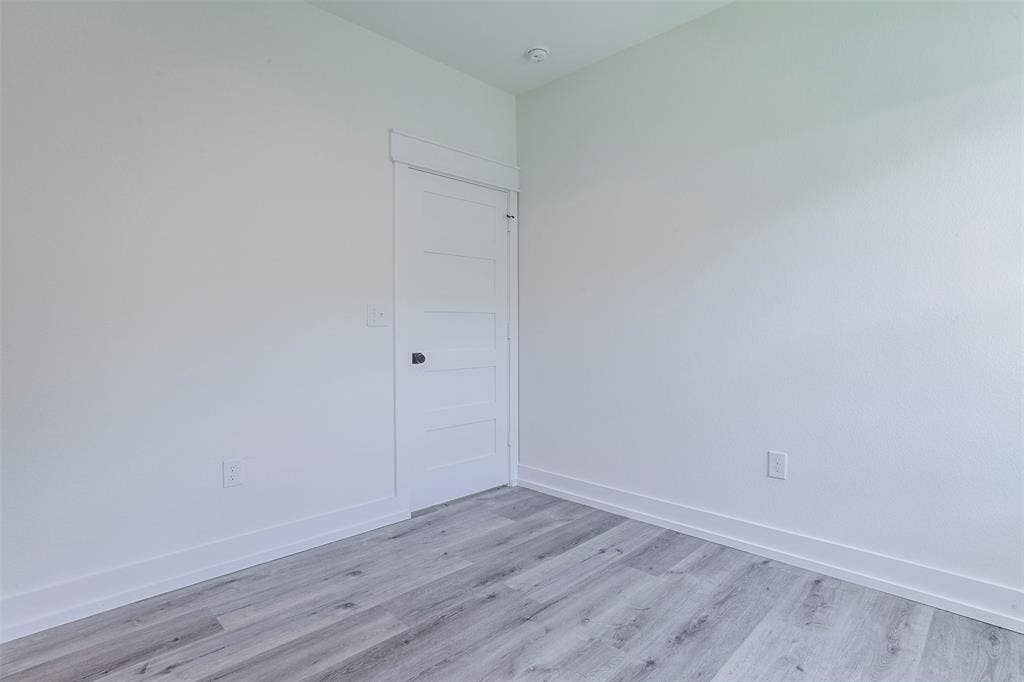 2608 Cleveland Avenue, Waco, TX 76711 Interior room featuring light gray wood-finish flooring, white walls, and a white paneled door with black hardware