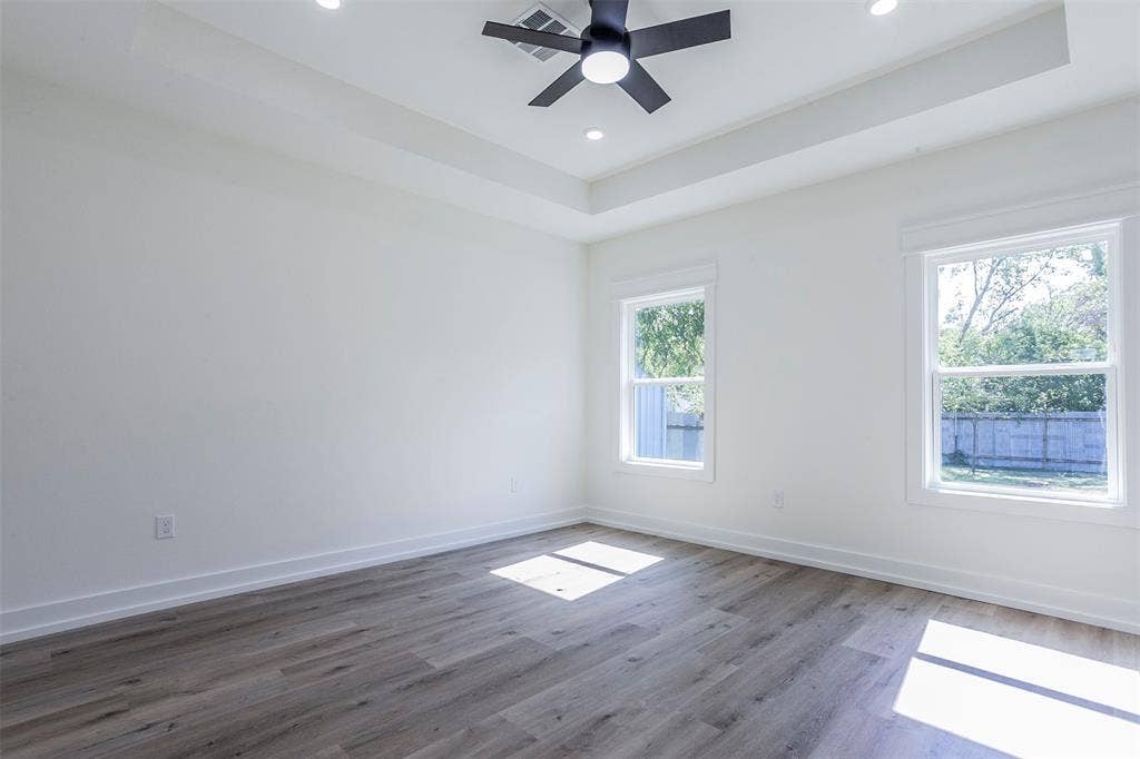 2608 Cleveland Avenue, Waco, TX 76711 Bright room featuring wood-finish flooring, two large windows, a tray ceiling, recessed lighting, and a ceiling fan