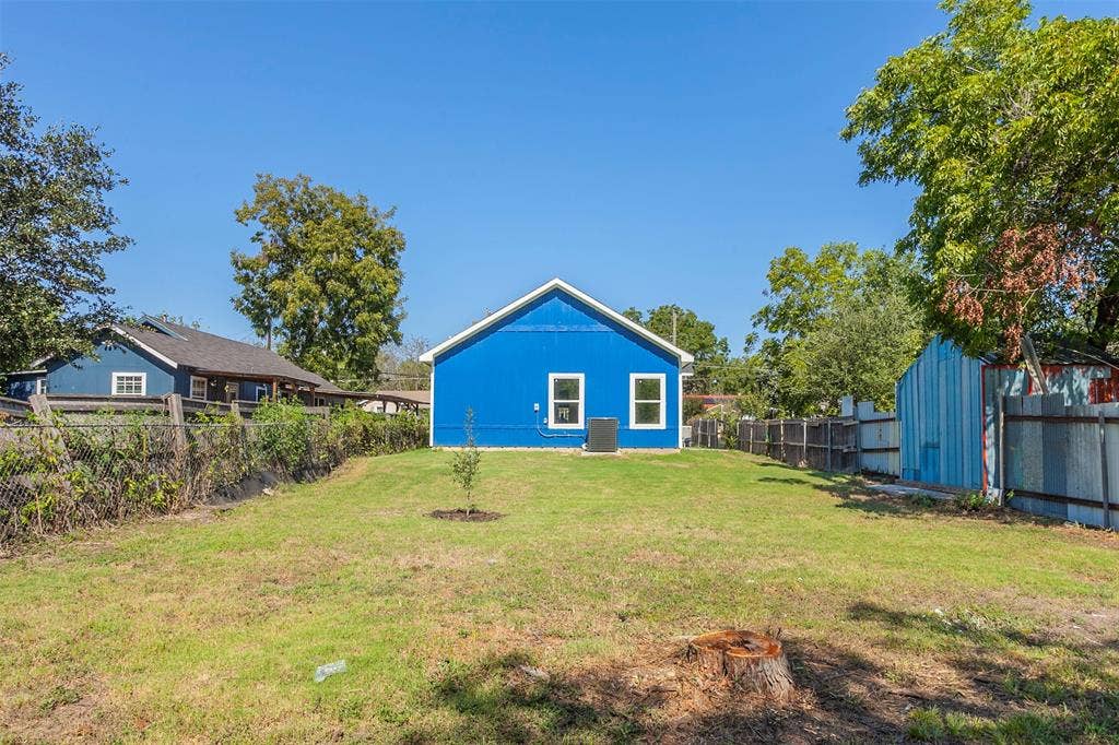 2608 Cleveland Avenue, Waco, TX 76711 Spacious backyard featuring a vibrant blue exterior, white trim windows, and mature trees