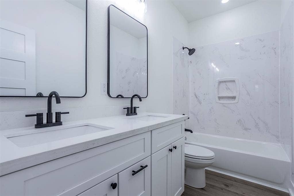 2608 Cleveland Avenue, Waco, TX 76711 Bathroom featuring a double vanity with matte black fixtures, integrated sinks, white countertops, and shaker-style cabinetry
