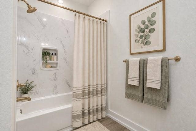 2608 Cleveland Avenue, Waco, TX 76711 Virtual staging -Bathtub with a built-in shower niche, brushed bronze fixtures, and a white marble-look shower surround