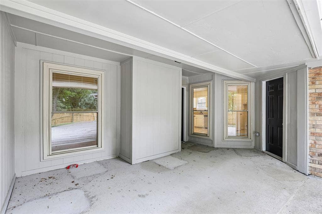 612 E Oak Street, Wylie, TX 75098 Covered patio with a concrete slab floor, light gray vertical paneling, and multiple windows with blinds
