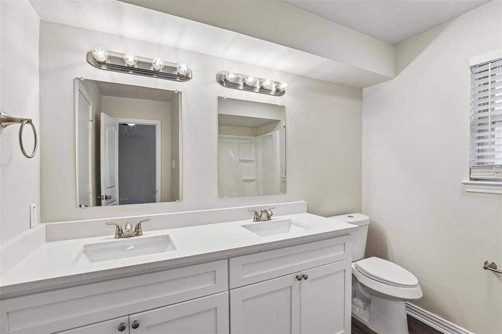612 E Oak Street, Wylie, TX 75098 Dual vanity with white cabinetry, integrated sinks, brushed nickel fixtures, and coordinating wall-mounted light bars
