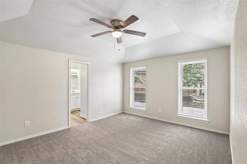 612 E Oak Street, Wylie, TX 75098 Spacious room featuring a tray ceiling, ceiling fan with integrated lighting, and two windows with blinds