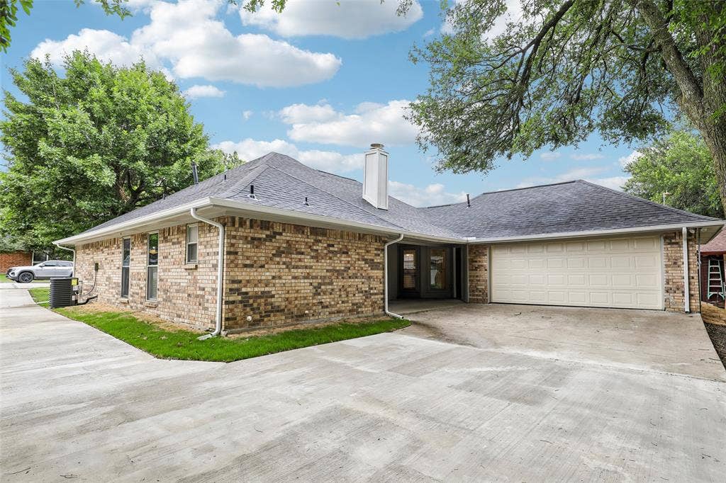 612 E Oak Street, Wylie, TX 75098 Exterior brick facade with a two-car garage, concrete driveway, and dark shingle roof