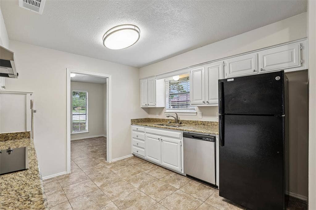 612 E Oak Street, Wylie, TX 75098 Kitchen featuring white shaker-style cabinetry, granite-finish countertops, tile flooring, and a stainless steel dishwasher