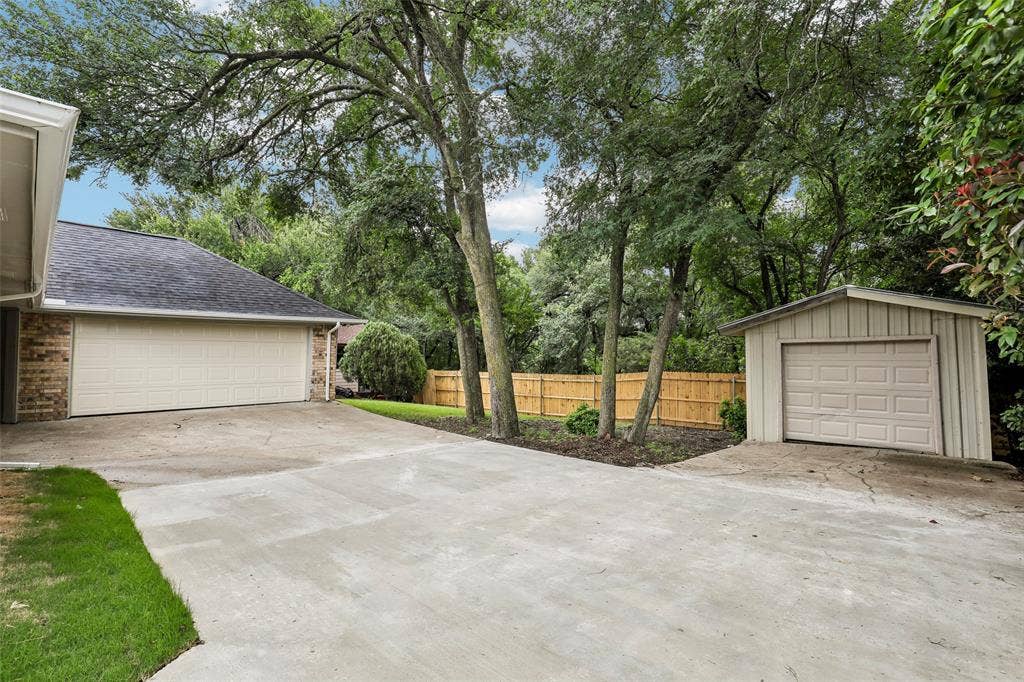 612 E Oak Street, Wylie, TX 75098 Expansive concrete driveway with a two-car garage and a detached single-car garage