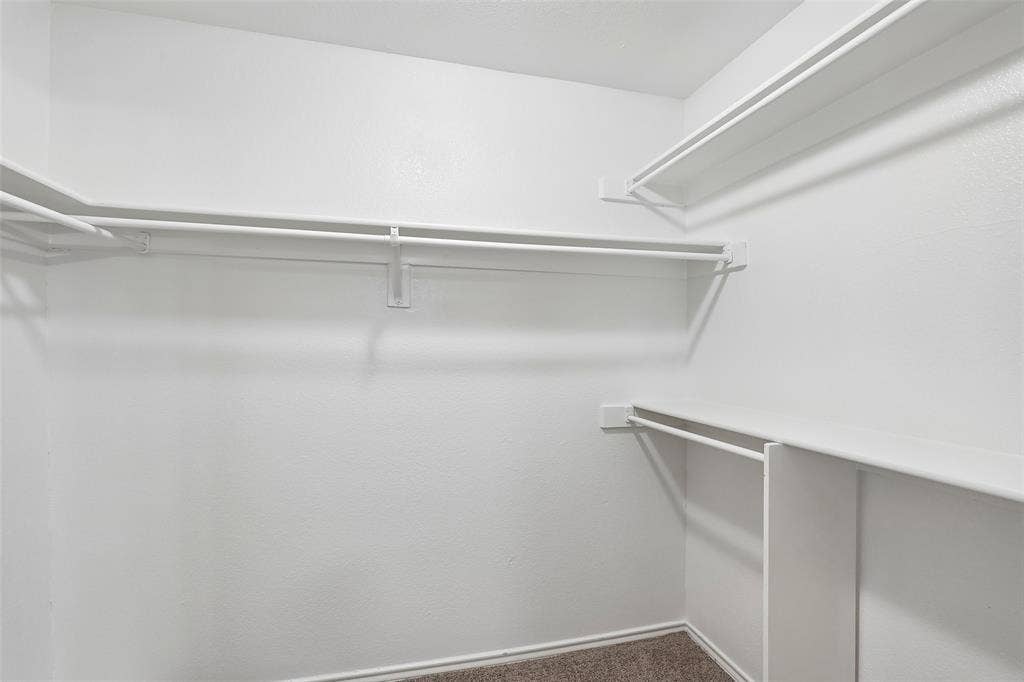 612 E Oak Street, Wylie, TX 75098 Walk-in closet featuring white wire shelving, hanging rods, and neutral-toned carpet flooring