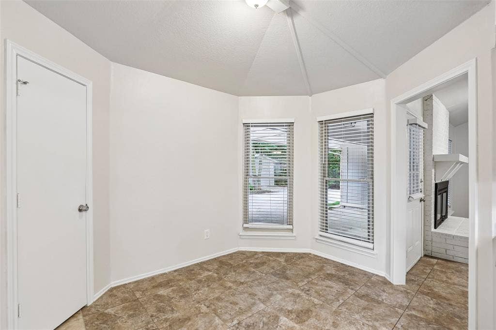 612 E Oak Street, Wylie, TX 75098 Bay window area featuring two windows with blinds, a vaulted ceiling, and neutral-toned tile flooring