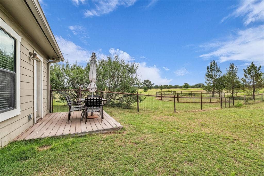 613 Bone Road, Valley Mills, TX 76689 Outdoor wooden deck with siding exterior, featuring a fenced pasture beyond the property line, mature trees, and an expansive lawn