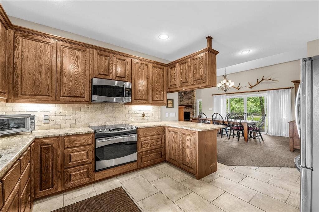 613 Bone Road, Valley Mills, TX 76689 Kitchen featuring wood cabinetry, stainless steel appliances, light-toned countertops, and a subway tile backsplash
