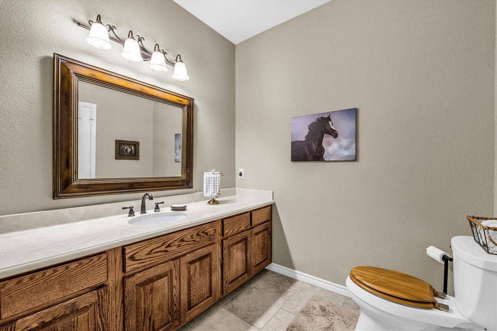 613 Bone Road, Valley Mills, TX 76689 Bathroom featuring a wood-finish vanity with ample storage, a white countertop, an undermount sink, and a framed mirror