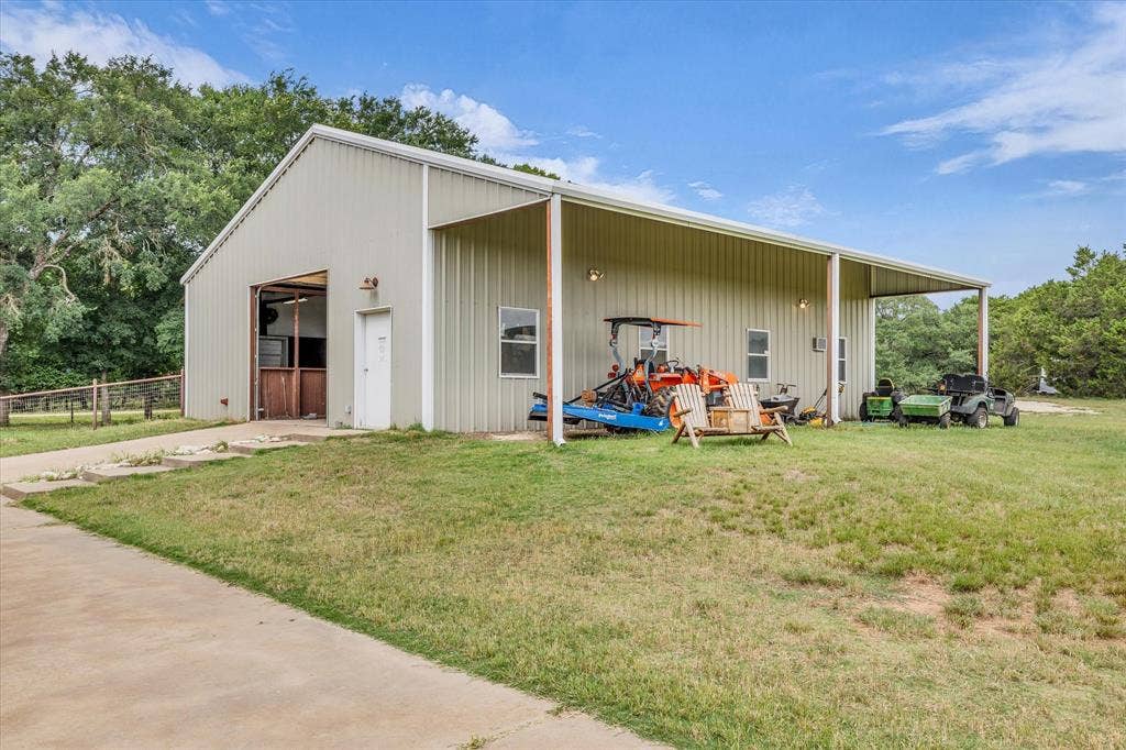 613 Bone Road, Valley Mills, TX 76689 Metal-sided outbuilding featuring a large roll-up door, an access door, and multiple windows